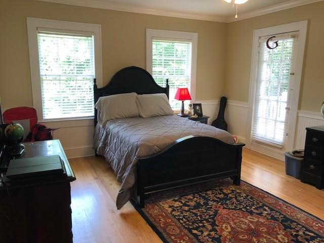 bedroom with multiple windows, light wood finished floors, and ornamental molding