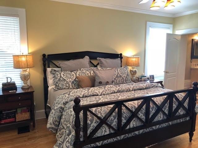 bedroom with crown molding, multiple windows, and wood finished floors