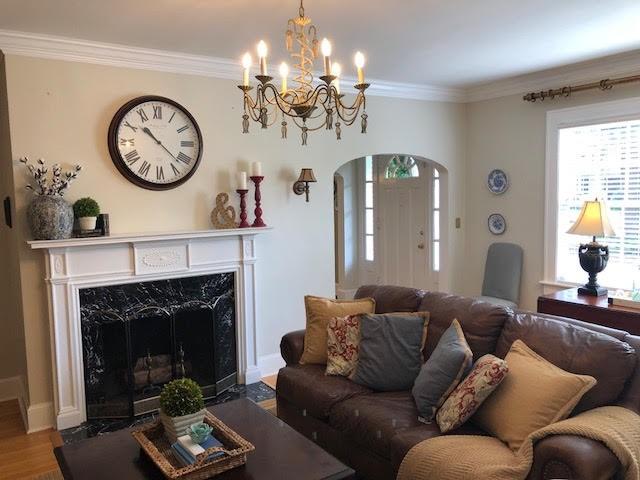 living room with ornamental molding, wood finished floors, arched walkways, a fireplace, and baseboards