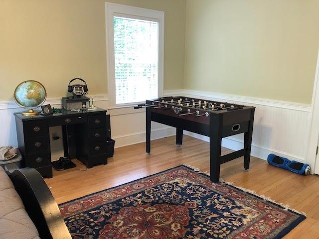 recreation room featuring a wainscoted wall and wood finished floors