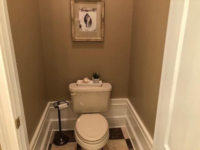 bathroom featuring a decorative wall, toilet, and wainscoting