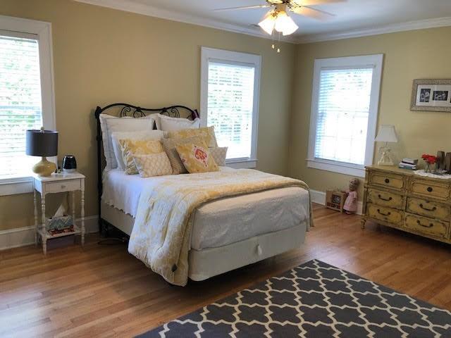 bedroom with multiple windows, wood finished floors, and ornamental molding