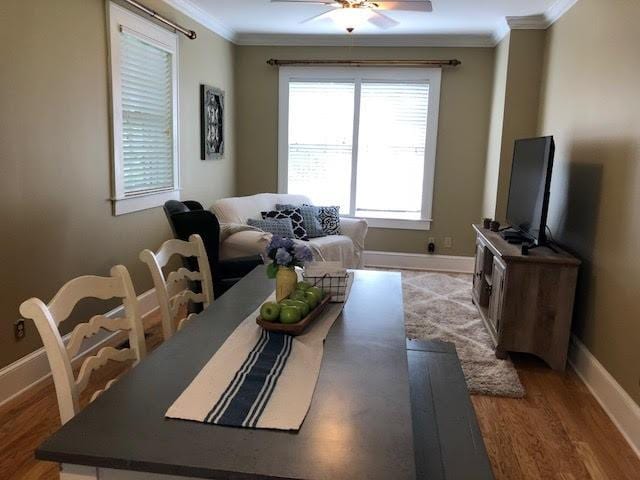 interior space featuring ceiling fan, light wood-type flooring, crown molding, and baseboards