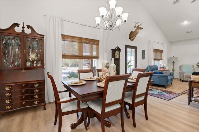 dining area with light wood finished floors, visible vents, a chandelier, and high vaulted ceiling