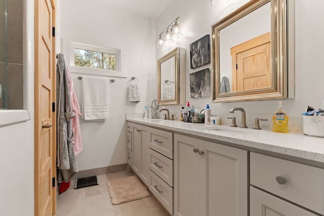 full bath featuring double vanity, visible vents, a sink, tile patterned flooring, and baseboards