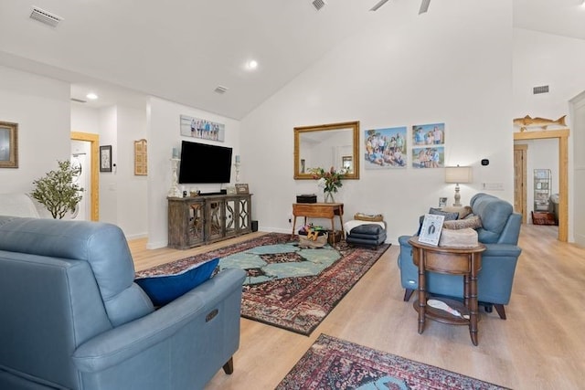 living room with light wood-type flooring, high vaulted ceiling, ceiling fan, and visible vents