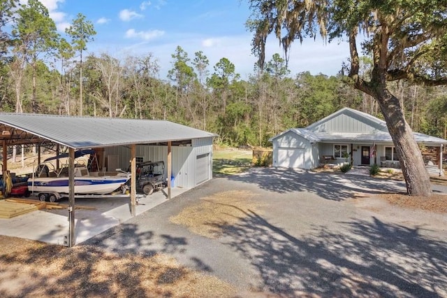 view of car parking with a garage, a forest view, and a carport