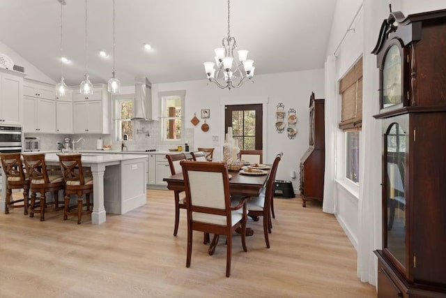 dining space featuring vaulted ceiling, light wood-type flooring, and a chandelier