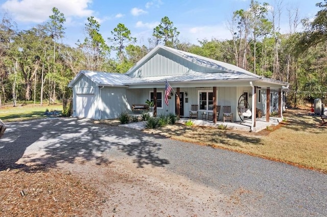 view of front facade with gravel driveway, covered porch, and metal roof