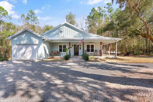 view of front of house with driveway, covered porch, an attached garage, and board and batten siding