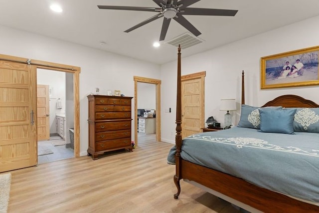 bedroom featuring a barn door, light wood-type flooring, visible vents, and recessed lighting