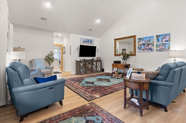 living room with light wood finished floors, visible vents, high vaulted ceiling, and recessed lighting