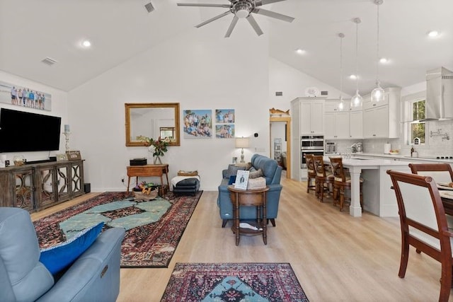 living area with high vaulted ceiling, light wood-style flooring, visible vents, and a ceiling fan