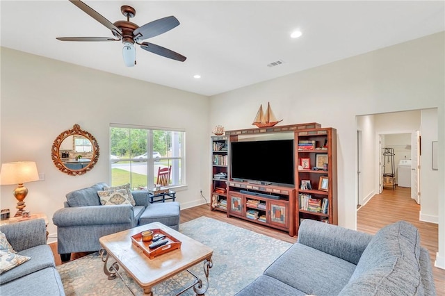 living room featuring ceiling fan, light hardwood / wood-style floors, and washer / dryer