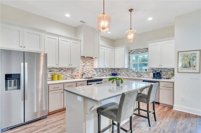 kitchen featuring white cabinetry, a center island, stainless steel appliances, light hardwood / wood-style flooring, and a breakfast bar