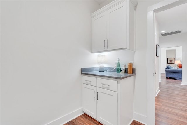 bar featuring white cabinets and light wood-type flooring