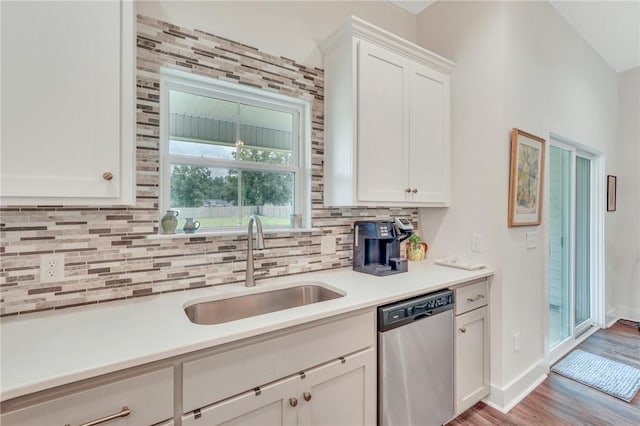 kitchen featuring backsplash, sink, light hardwood / wood-style flooring, dishwasher, and white cabinetry