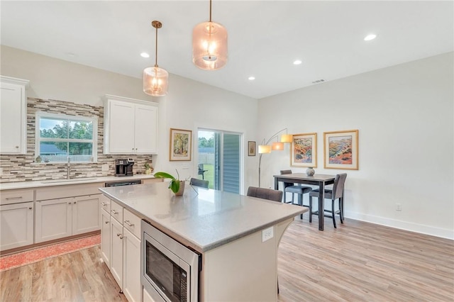 kitchen featuring white cabinetry, stainless steel microwave, a healthy amount of sunlight, and sink