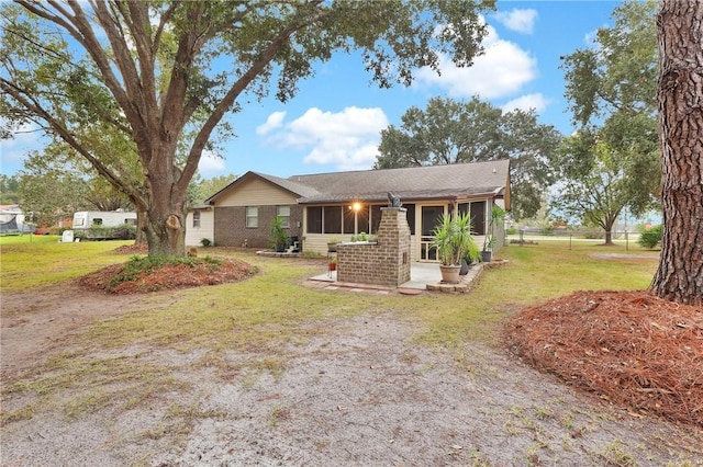 ranch-style home with a sunroom, a patio area, and a front lawn