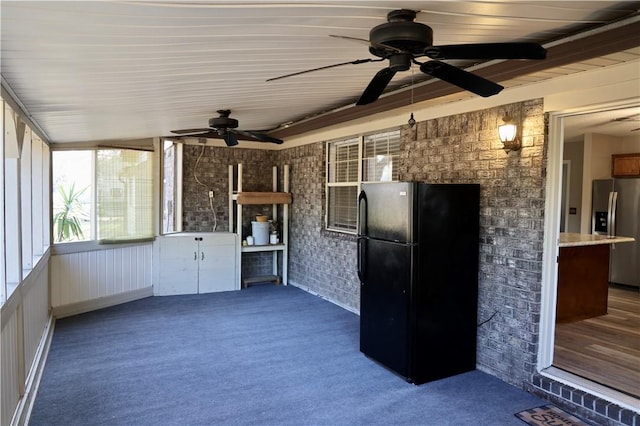 interior space with black fridge, white cabinetry, stainless steel fridge, carpet floors, and brick wall