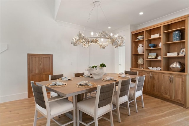 dining space with light hardwood / wood-style floors and an inviting chandelier