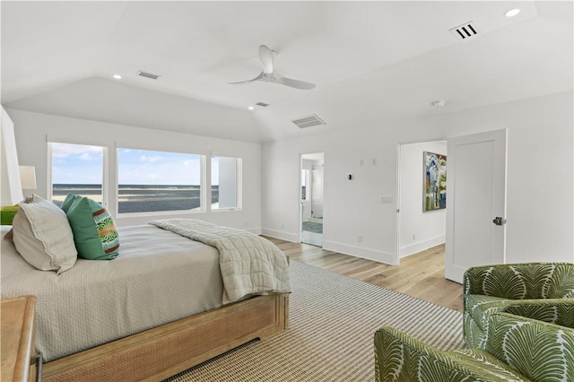 bedroom with a water view, ensuite bath, vaulted ceiling, ceiling fan, and light hardwood / wood-style floors