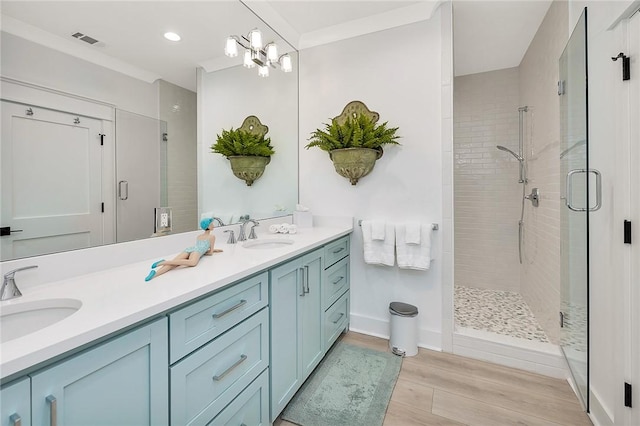 bathroom with vanity, a shower with door, crown molding, a notable chandelier, and wood-type flooring