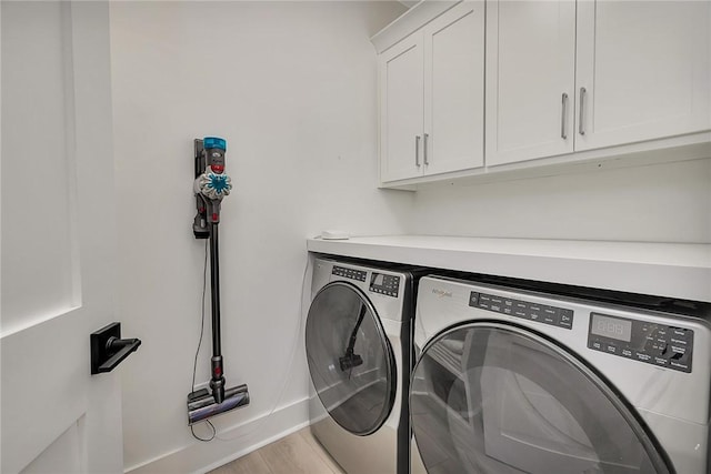 laundry area featuring washer and clothes dryer, cabinets, and light hardwood / wood-style floors