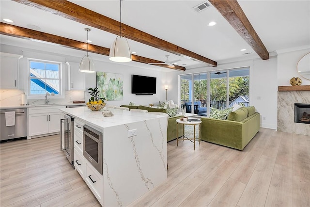 kitchen featuring pendant lighting, white cabinets, light wood-type flooring, a kitchen island, and stainless steel appliances