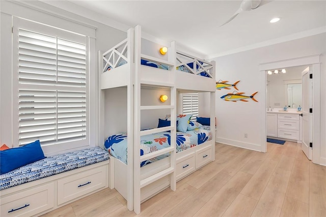 bedroom with ensuite bath, ceiling fan, light hardwood / wood-style flooring, and multiple windows