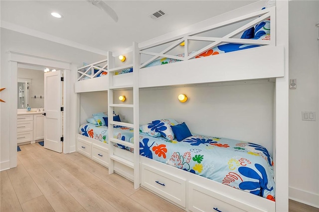 bedroom with ensuite bath, ceiling fan, and light hardwood / wood-style flooring