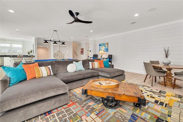 living room featuring ceiling fan, light hardwood / wood-style floors, and ornamental molding