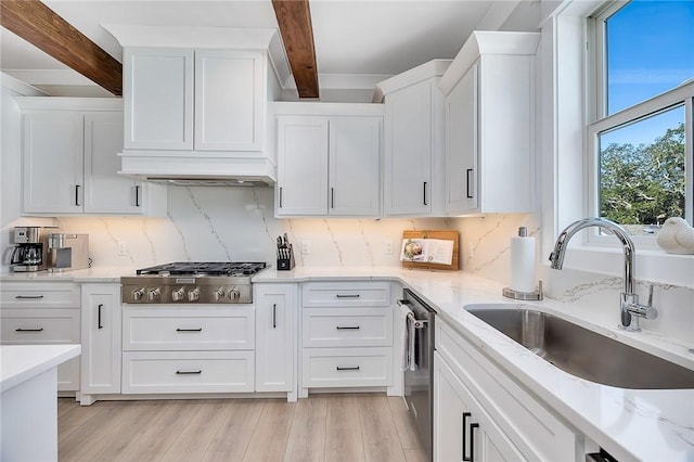 kitchen with white cabinets, stainless steel appliances, sink, light hardwood / wood-style flooring, and beamed ceiling