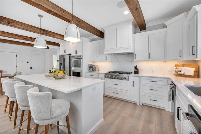 kitchen with white cabinets, beamed ceiling, stainless steel appliances, and a kitchen island