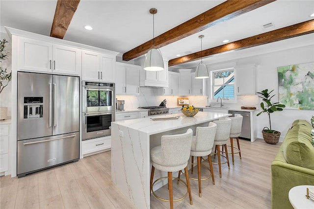 kitchen with a center island, sink, appliances with stainless steel finishes, beam ceiling, and white cabinetry