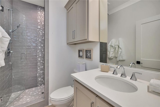 bathroom with vanity, toilet, a shower with door, and ornamental molding