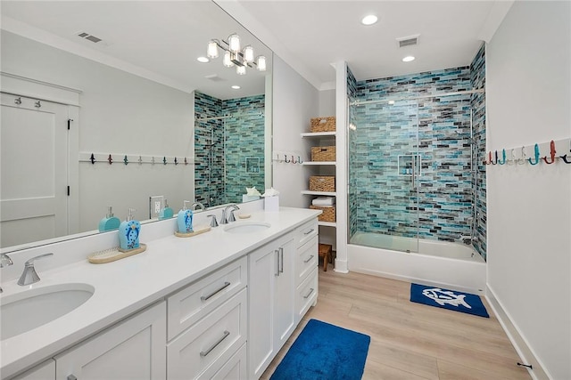 bathroom featuring vanity, crown molding, wood-type flooring, and bath / shower combo with glass door