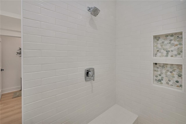 bathroom featuring hardwood / wood-style floors and a tile shower