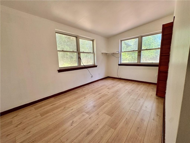 unfurnished room with baseboards, plenty of natural light, and light wood-type flooring