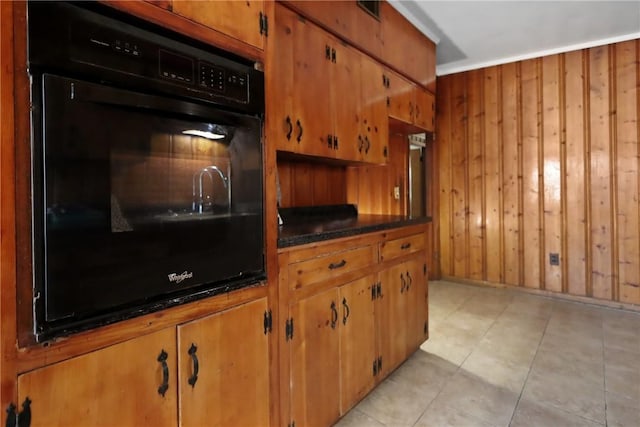4365 US Highway 341, Jesup, GA 31545 - kitchen with black oven, brown cabinetry, wooden walls, dark countertops, and light tile patterned floors