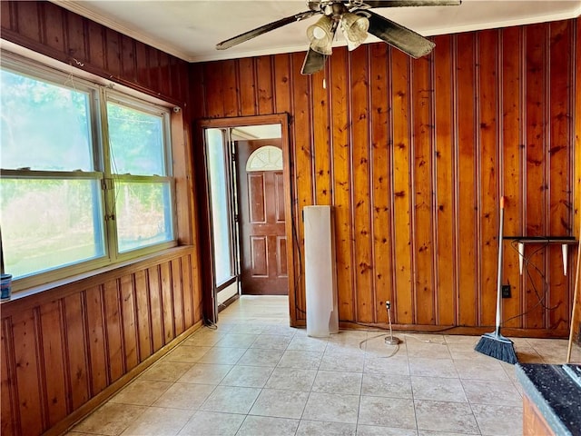 unfurnished room featuring crown molding, ceiling fan, wood walls, and light tile patterned floors