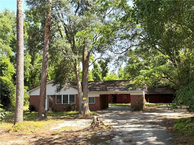 ranch-style home featuring brick siding, aphalt driveway, and an attached carport