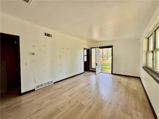 spare room featuring baseboards, light wood-style flooring, and visible vents