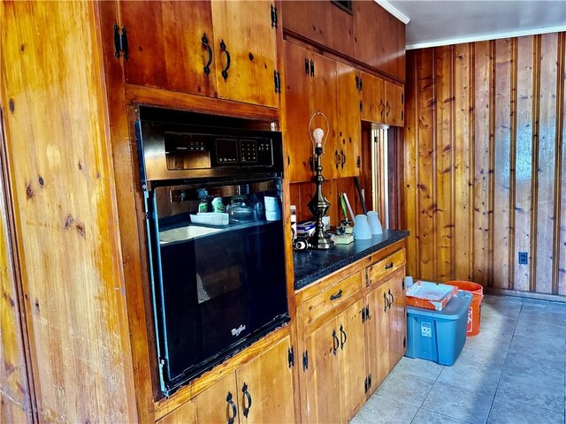 bar featuring black oven, light tile patterned floors, and wooden walls