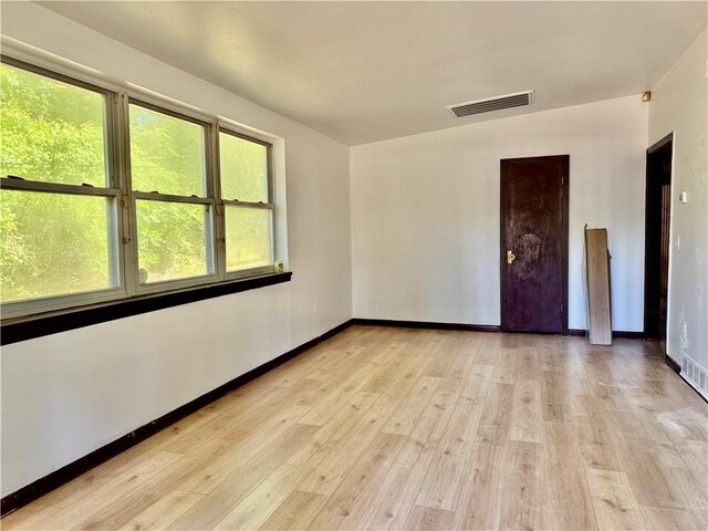 spare room featuring visible vents, light wood finished floors, and baseboards