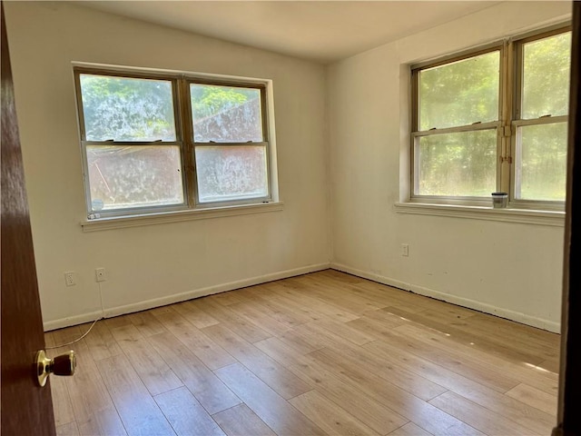 unfurnished room featuring light wood-style floors, baseboards, and plenty of natural light