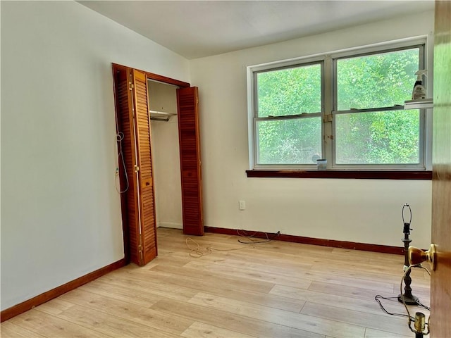 unfurnished bedroom with baseboards, light wood finished floors, and a closet