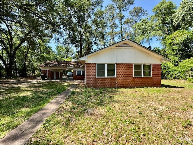 exterior space with brick siding, a yard, and an attached carport