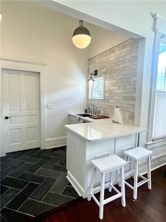 1915 Union St, Brunswick, GA 31520 - kitchen with a peninsula, decorative backsplash, a breakfast bar area, baseboards, and plenty of natural light