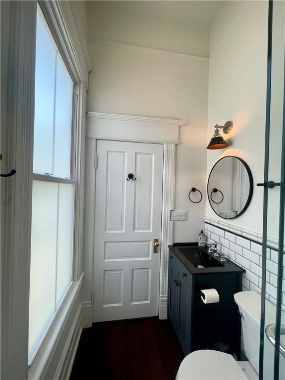 1915 Union St, Brunswick, GA 31520 - half bath featuring healthy amount of natural light, toilet, vanity, tile walls, and wood finished floors